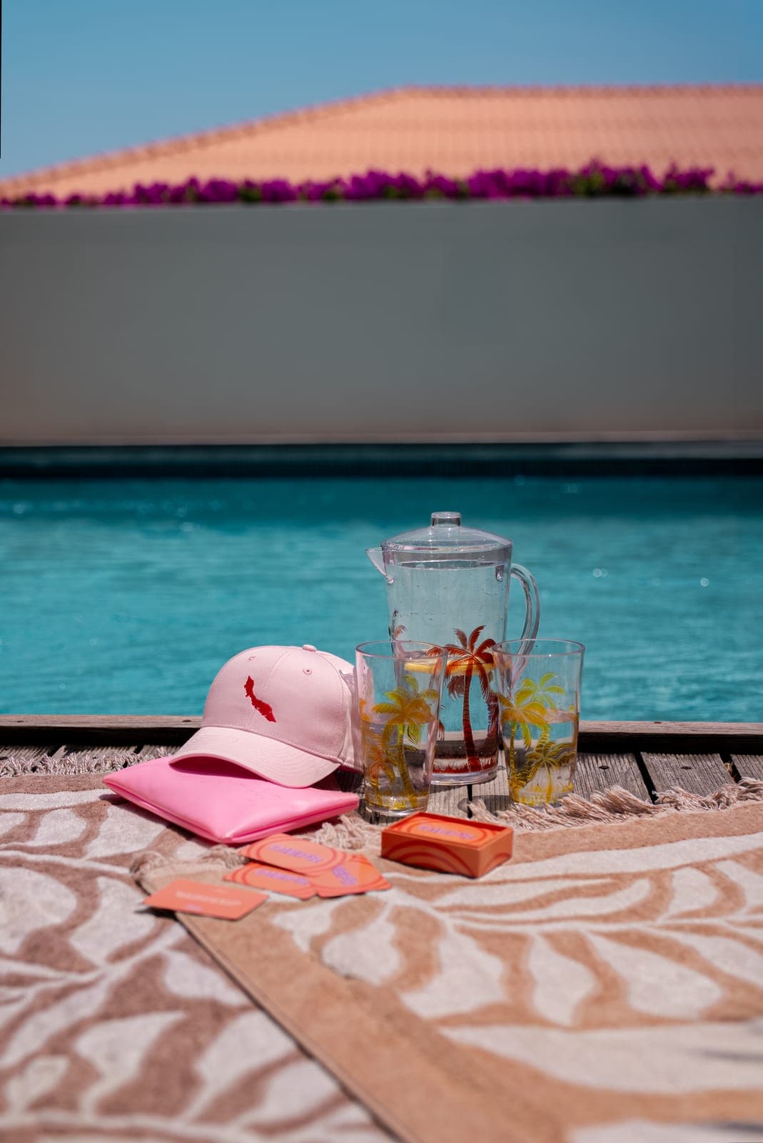 Kan limonade met palmboomglazen en roze pet op de vlonder aan het zwembad